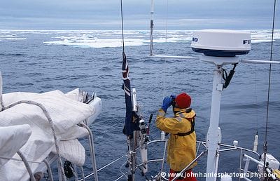 The stern of aluminum sailboat Morgan's Cloud showing the radar mast and antennas, taken in Hinlopen Strait, Svalbard, with pack ice closing in behind