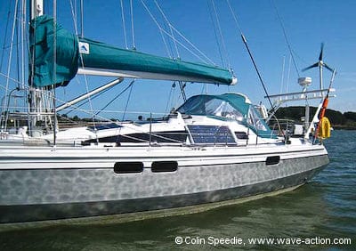 An OVNI 435 aluminum sailboat at anchor with portable solar panel against cabin side