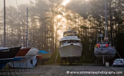 Aluminum sailboat Morgan's Cloud on popstands sheltered by tall trees at Bock Marine
