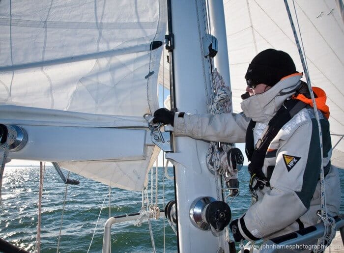 Nearly done. Phyllis drops the tack ring over the horn at the goose neck. There is one tack ring each side connected together with strong webbing through the reef cringle.