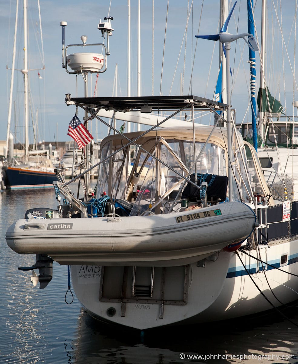 A sailboat stern festooned with dinghy in davits, solar panel, windmill, etc.