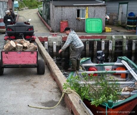 A man unloads wood from a speedboat and into an ATV in LaPoile, Newfoundland