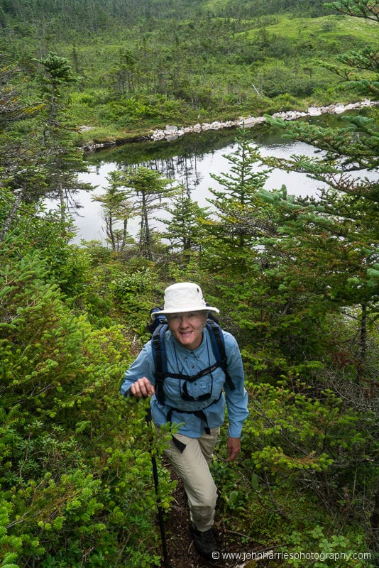 Woman on trail in woods with pond behind