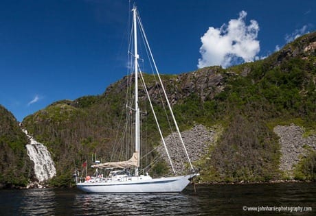 Sailboat Morgan's Cloud at anchor in front of waterfall, Hermitage Bay, Newfoundland JHH5II-18639