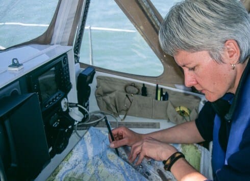 Woman in sailboat cockpit plotting on paper chart Scanned With Provia Profile